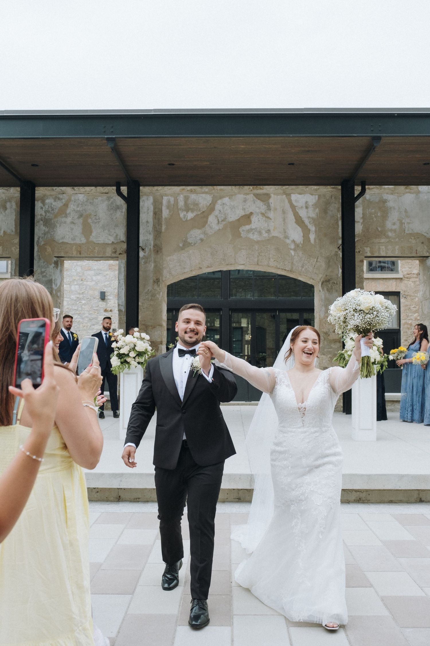 Happy newlyweds celebrating with guests as they exit their wedding ceremony in formal attire.