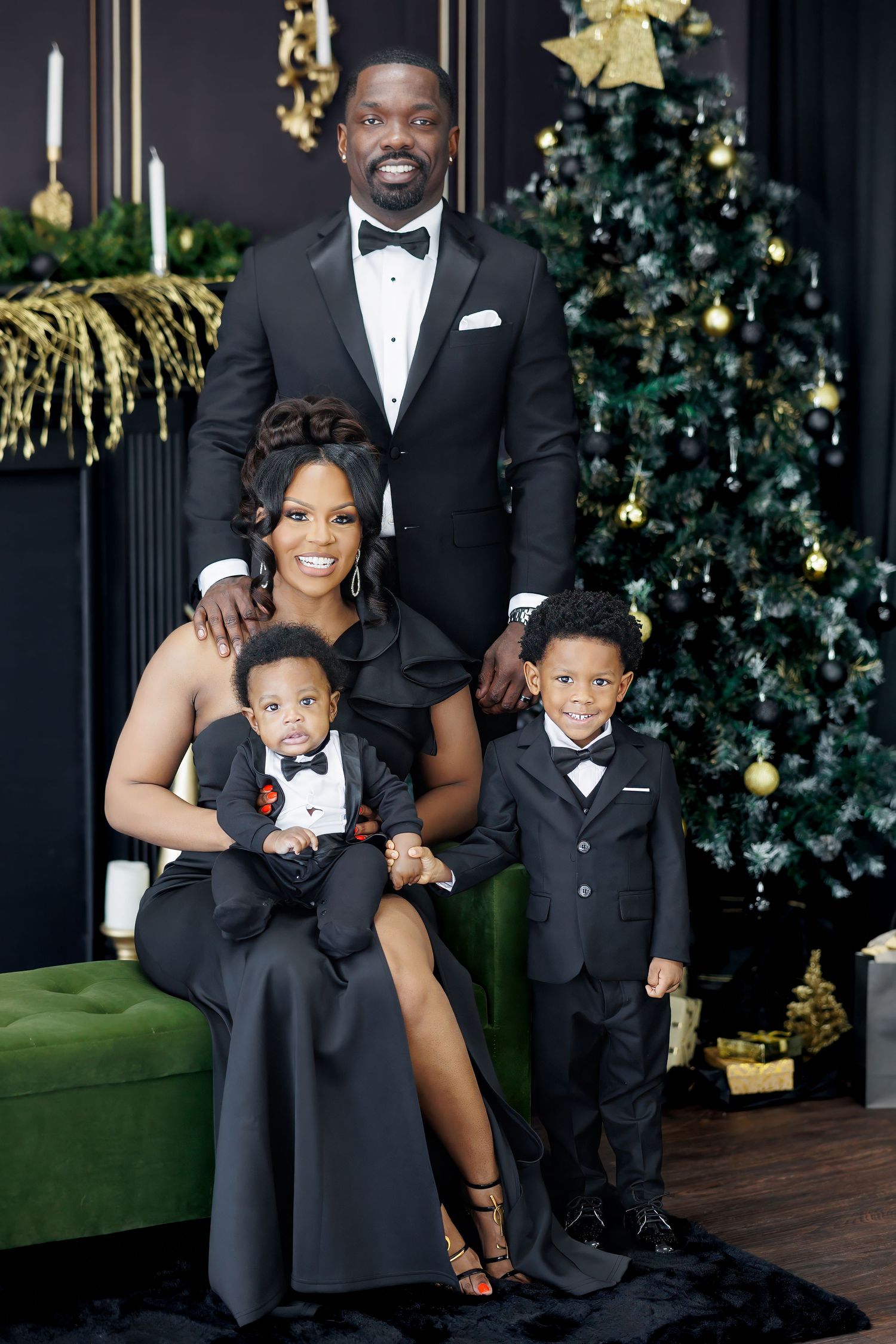 Elegant family portrait in formal attire posing by a decorated Christmas tree with green velvet seating at a Dallas holiday photoshoot