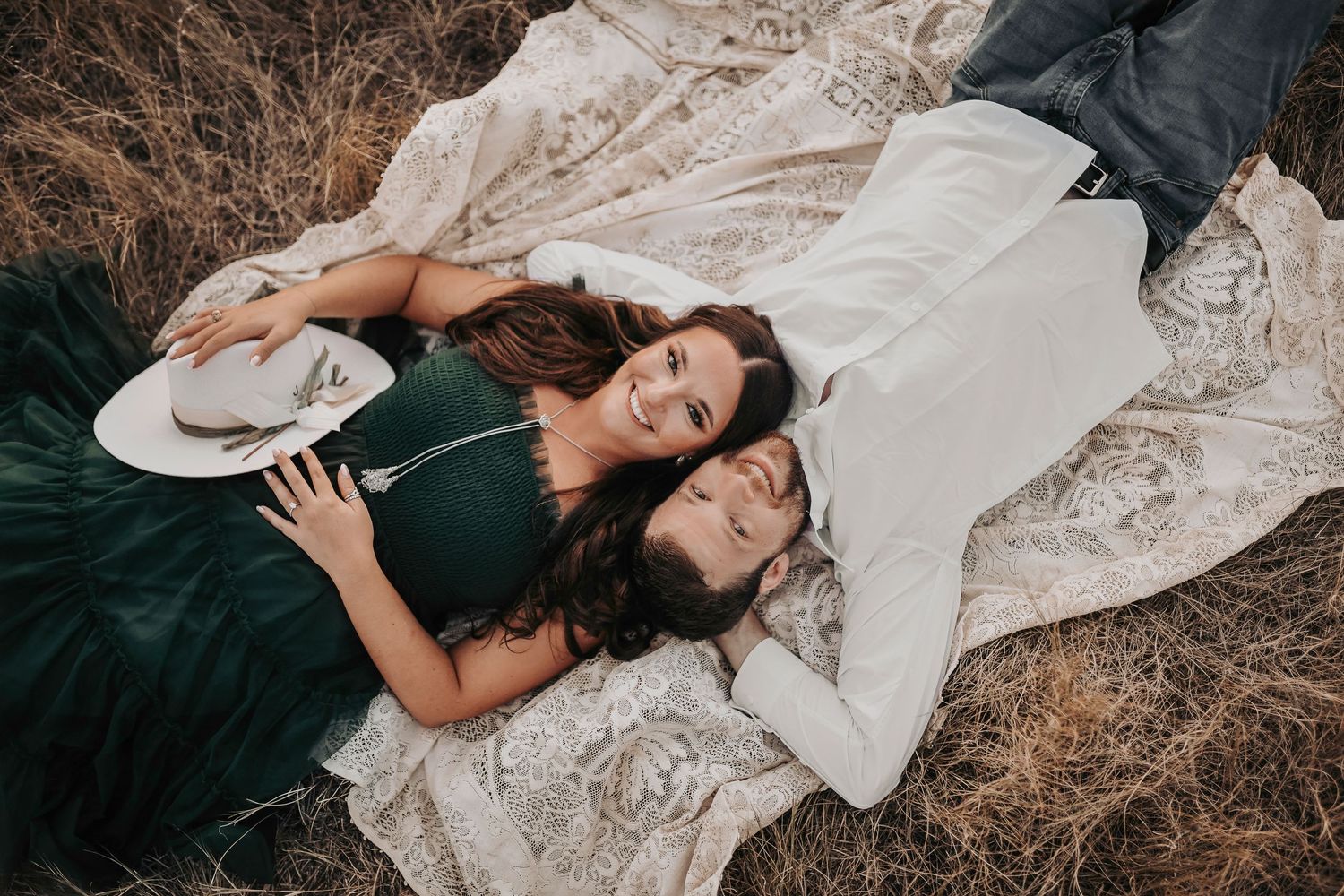 a photo of a romantic couple laying in the grass during golden hour on lake grapevine during their engagement photos