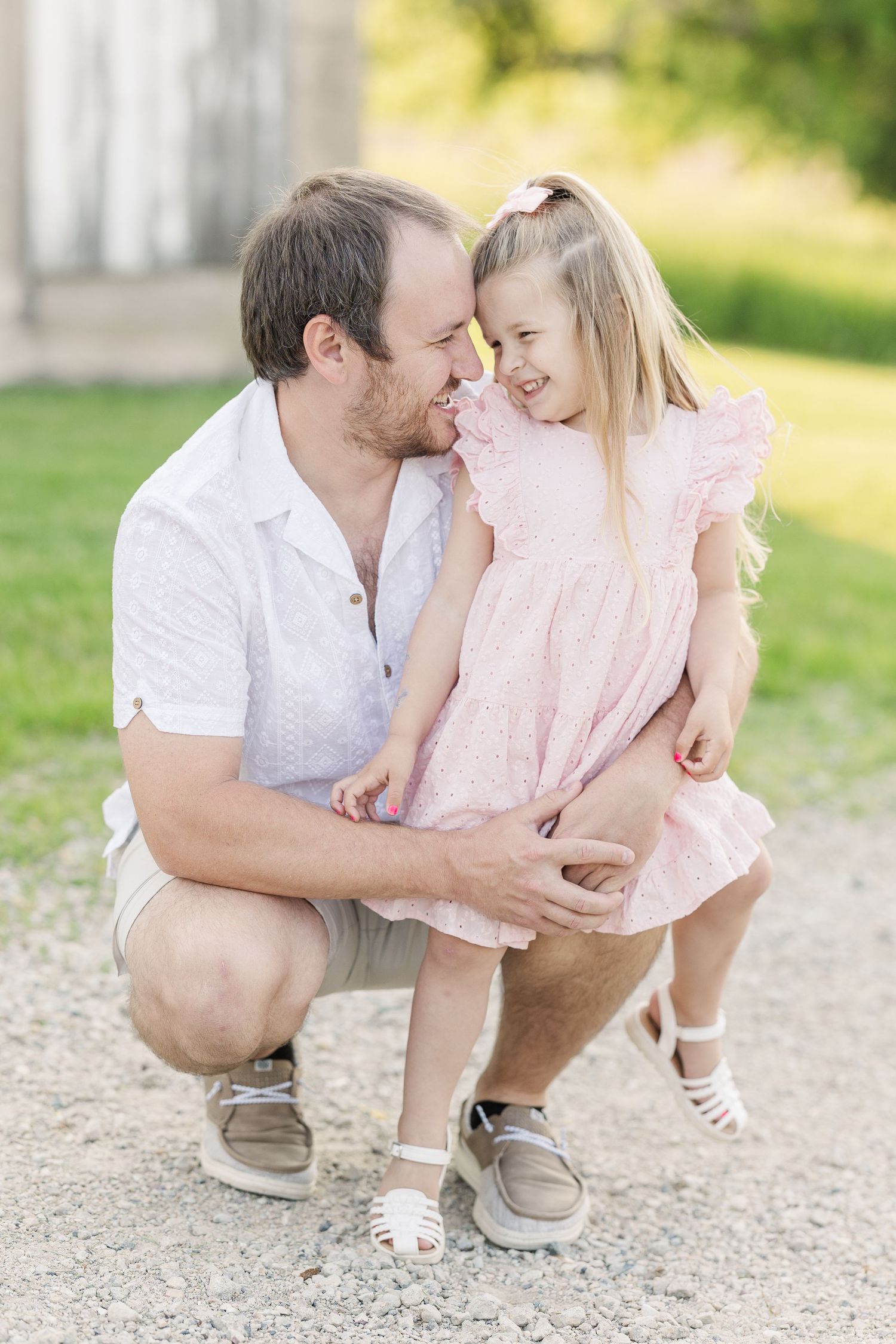Family shares tender embrace outdoors on gravel path against blurred natural background.