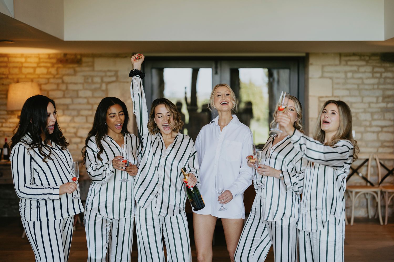 A group stands together at a wedding event wearing matching striped sleepwear and robes during pre-ceremony preparations.