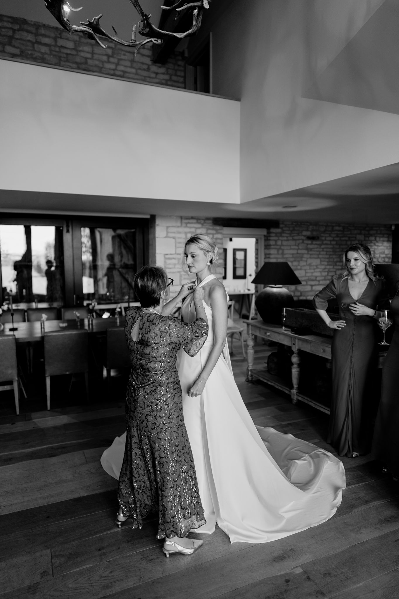 A black and white wedding photo showing preparations in an elegant room with exposed brick walls and hardwood floors.