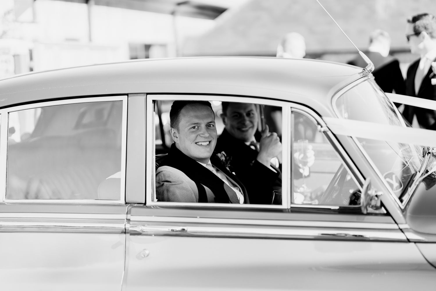 Black and white vintage photo of car passengers inside a classic automobile peering through the window.