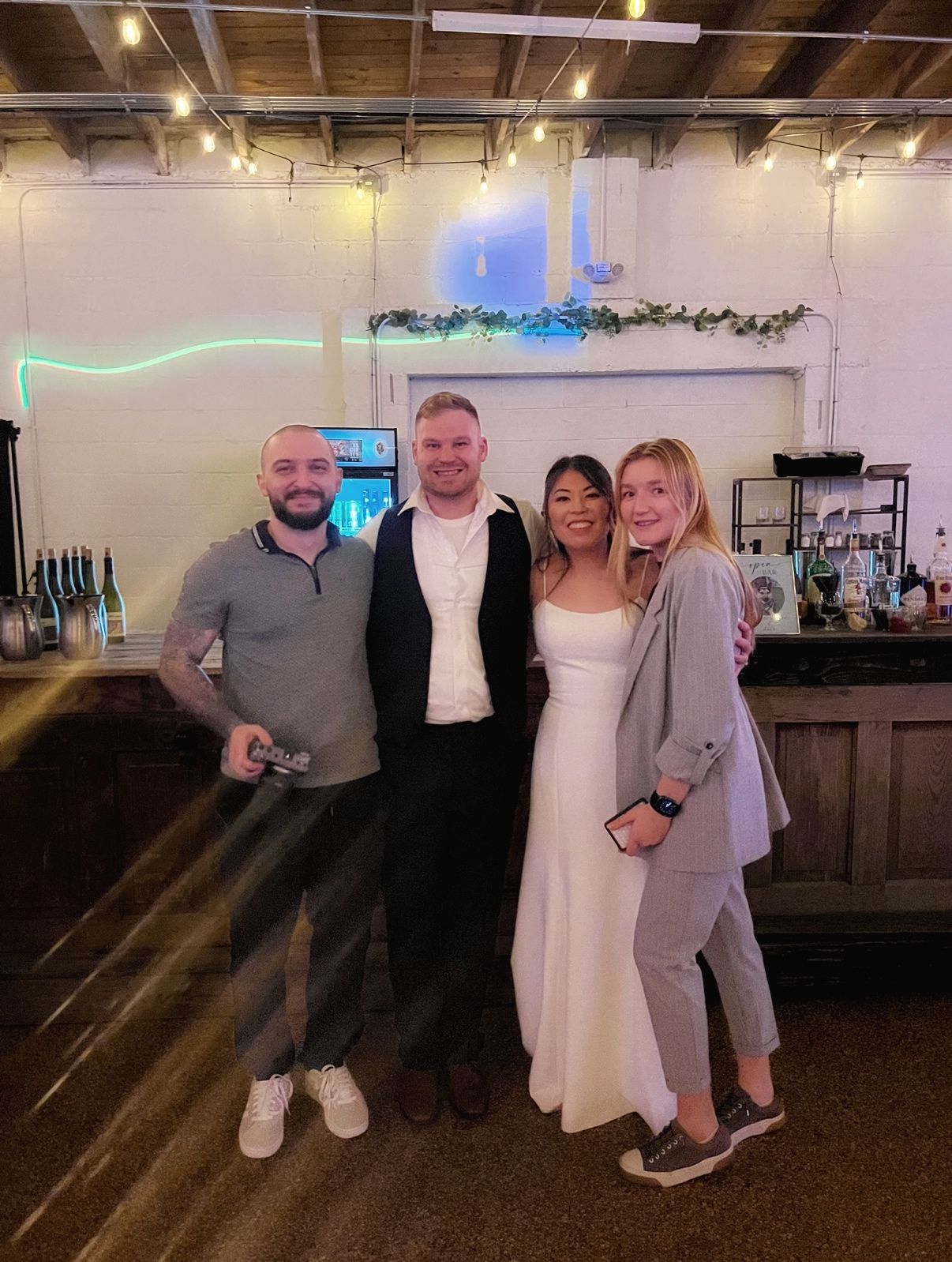 Group celebrating at an indoor venue with rustic bar and neon lighting decor.