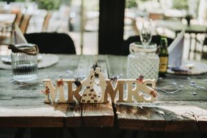Decorative 'Mr & Mrs' sign on rustic table setting at wedding reception.
