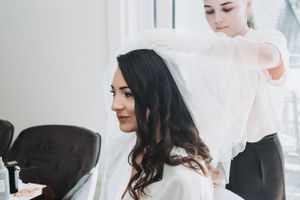 Wedding preparation scene showing stylist arranging bridal veil.