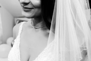 Close-up black and white detail of bridal necklace and lace dress.