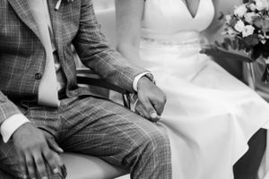 Black and white photo of couple in wedding attire sitting together.
