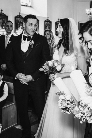 Black and white church ceremony with wedding party holding bouquets.