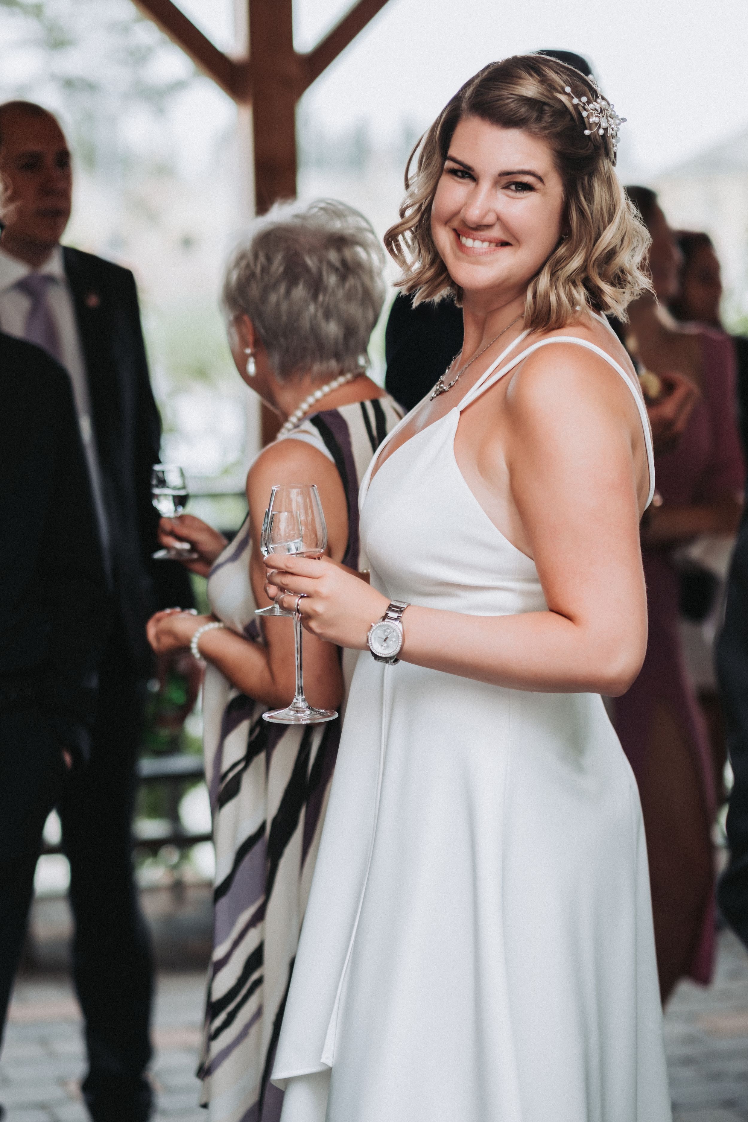 Candid reception photo of bride in white dress holding champagne glass.