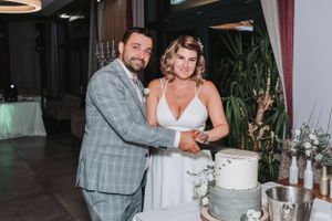 Newlyweds cutting their elegant white wedding cake together at reception.