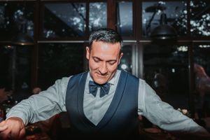 A groom in vest and bowtie dancing and celebrating at the wedding reception.