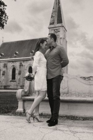 Romantic black and white portrait of couple kissing near historic church spire.