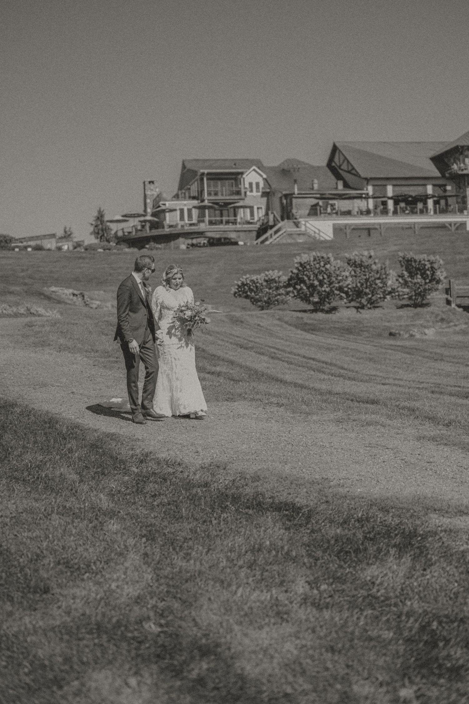 Vintage black and white photo by Samantha Campbell Imagery of a couple standing on a grassy hill with coastal houses in the background.