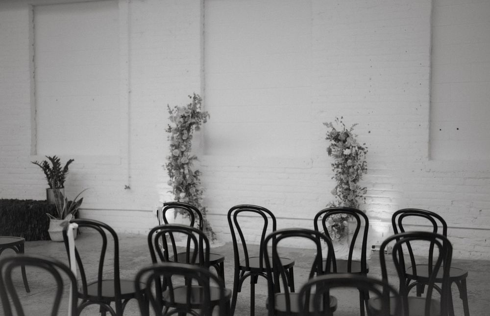 Black bentwood chairs arranged in rows with botanical wall decorations in black and white.