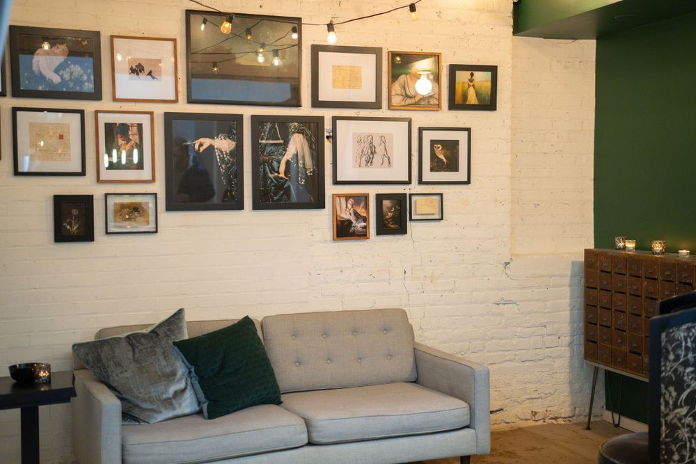 Contemporary lounge area with gray sofa and gallery wall of framed photographs on white brick wall.