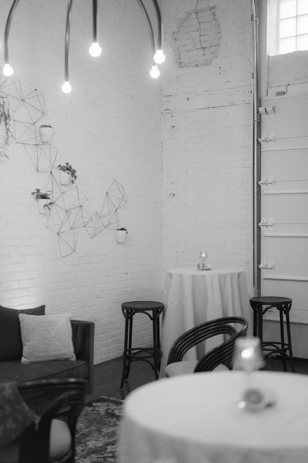 Minimalist corner with pendant lights, geometric wall art, and bistro tables.