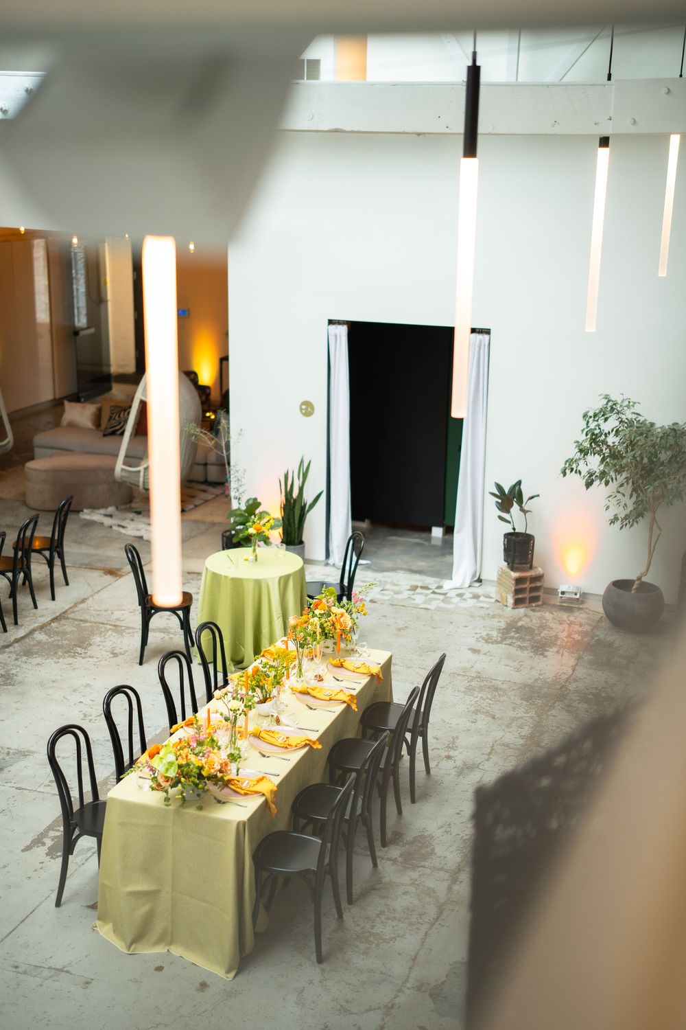 Yellow tablecloth-covered dining setup with black chairs in a modern industrial space.