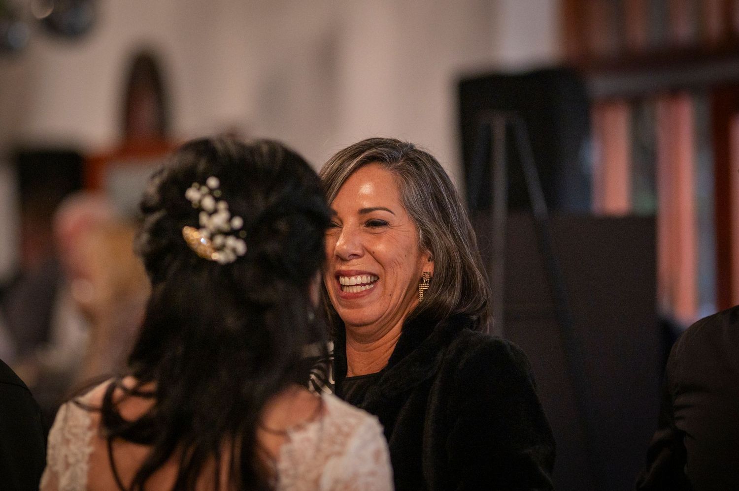 Two people share a joyful moment of laughter during what appears to be an indoor event or celebration.