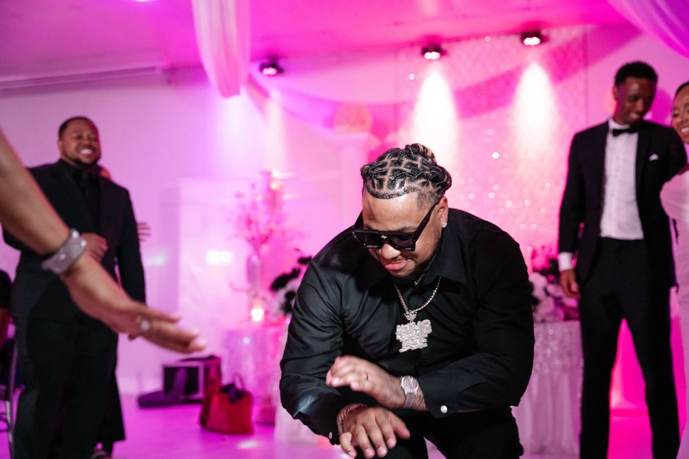 Wedding guests dance and celebrate on a pink-lit dance floor during an evening reception.