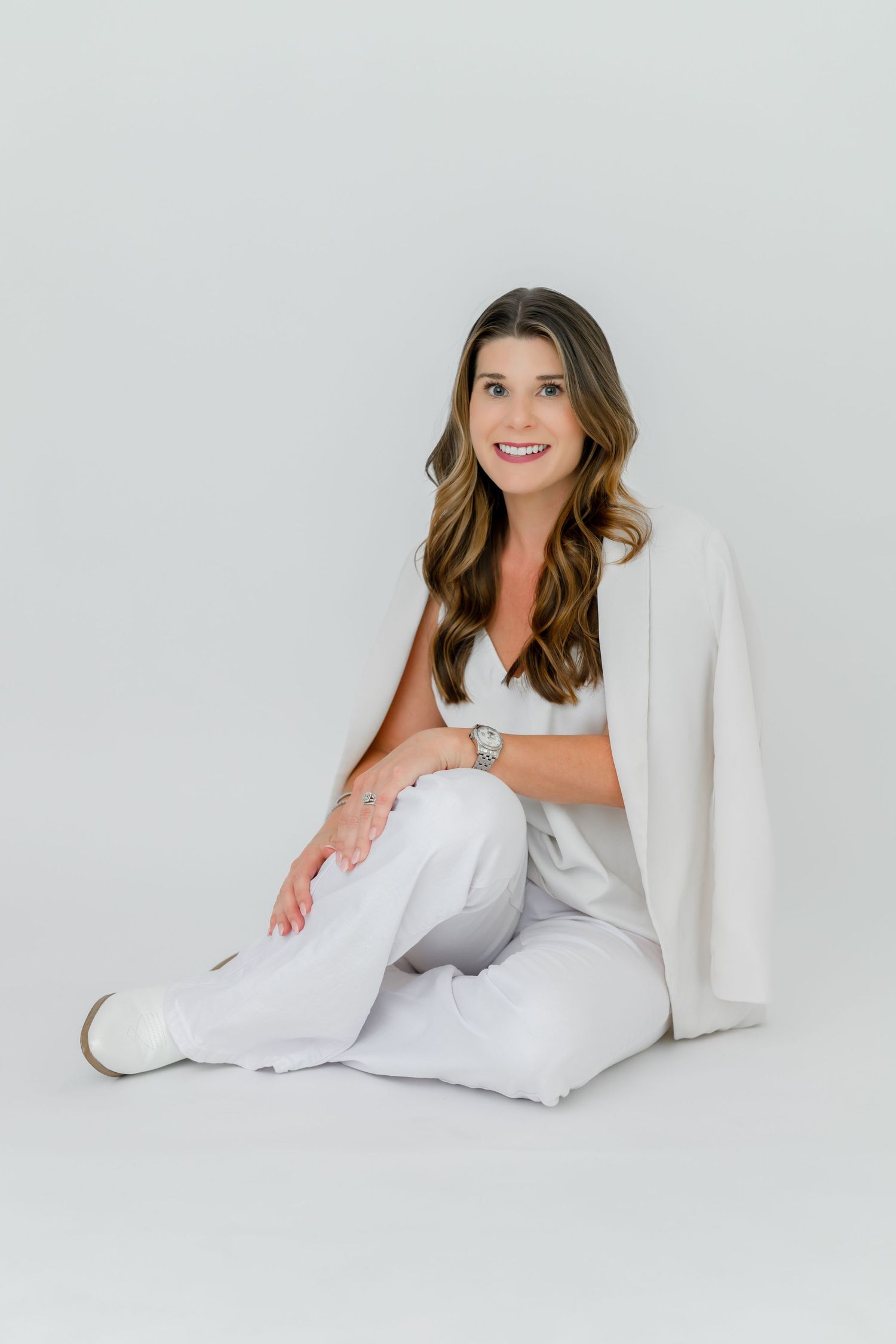 Professional studio portrait in all-white attire against light background.