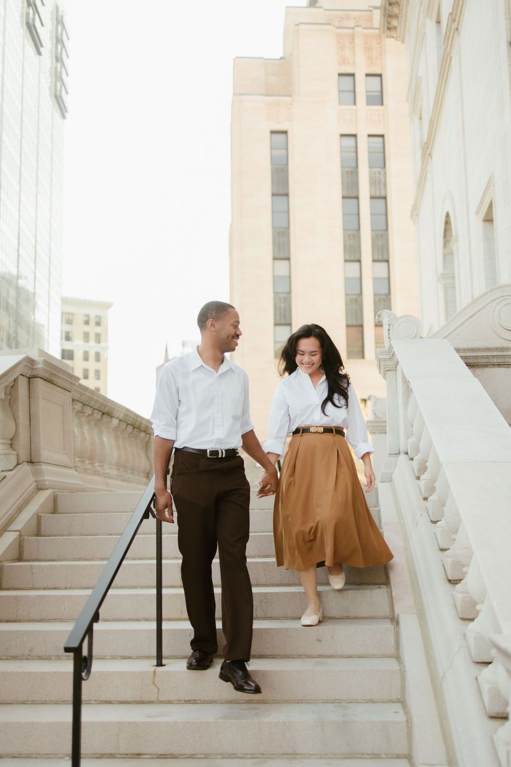 A couple descends elegant stone steps outside a historic building.