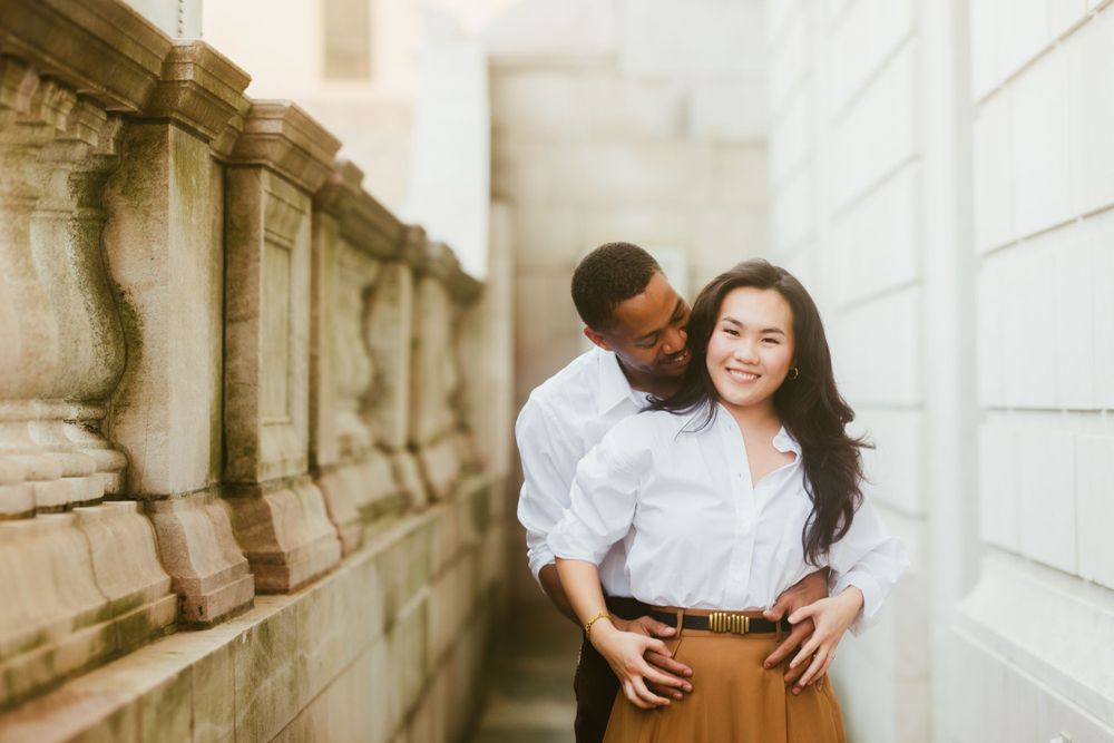 A couple shares a lighthearted moment in an outdoor stone passageway.