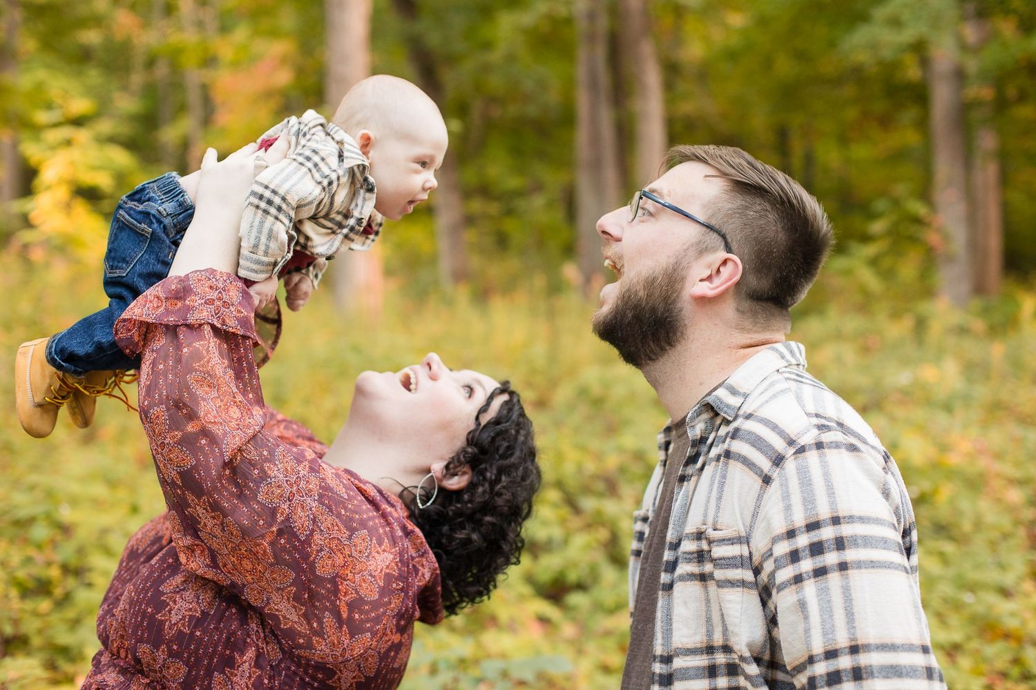 Mom and dad holding baby up in the air and laughing
