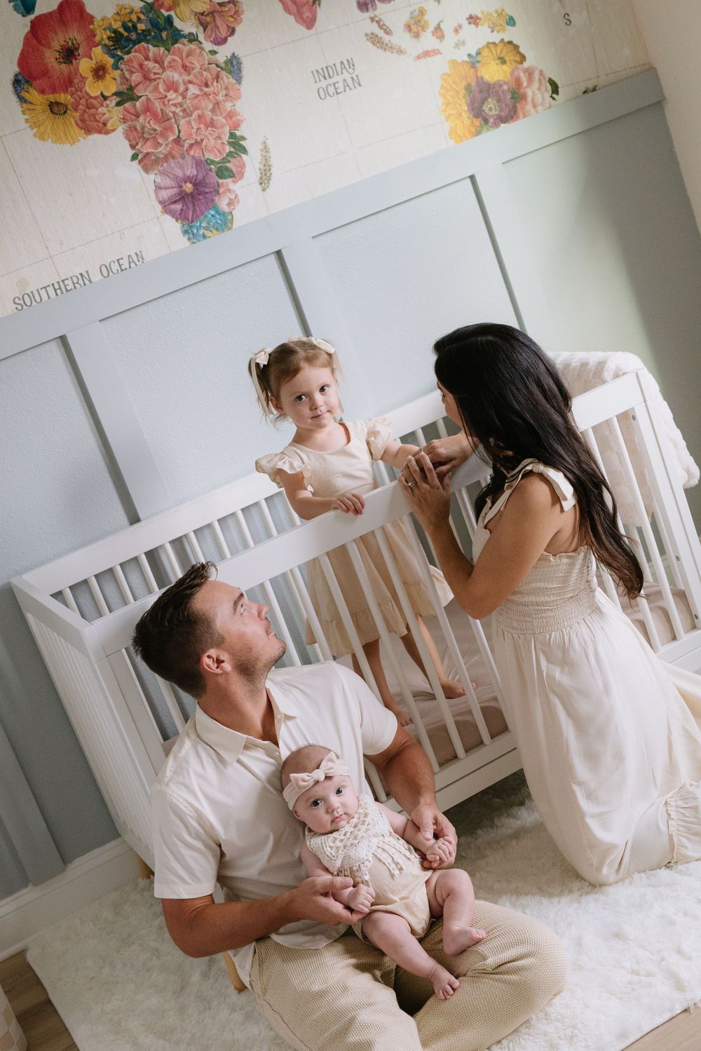Family spending quality time together in a nursery room decorated with floral art and white furniture.