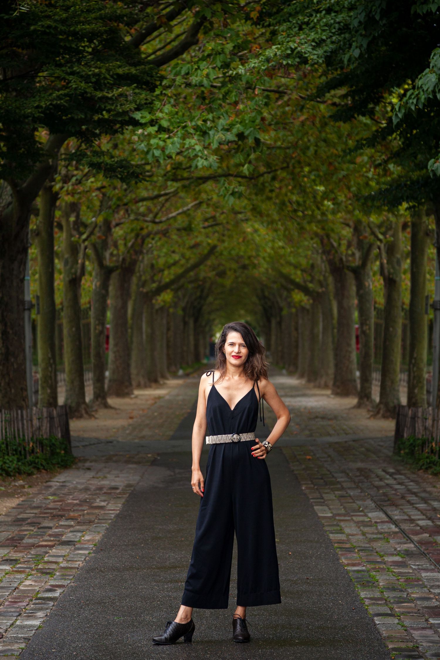 Tree-lined autumn pathway with symmetrical composition and figure in black attire.