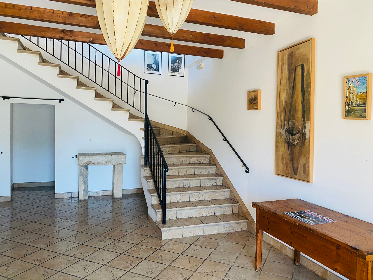 Elegant curved staircase with exposed wooden beams and decorative details in Mediterranean-style entryway.