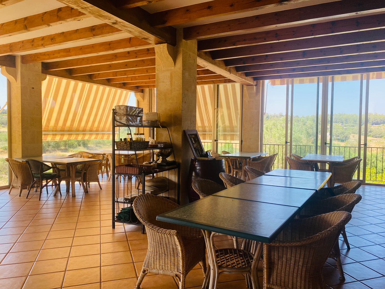 Modern dining room with panoramic windows showcases wooden beams, tiled floors and expansive mountain views.