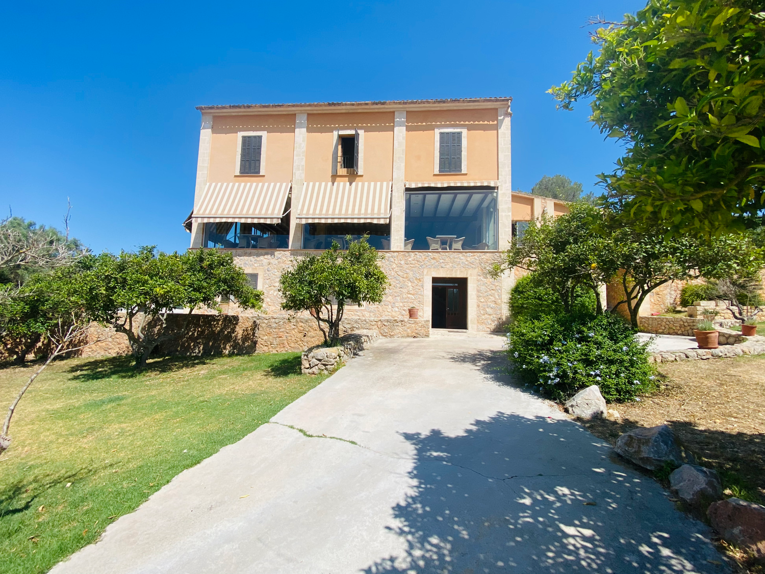 Mediterranean villa with stone facade and surrounding greenery on a hillside property.