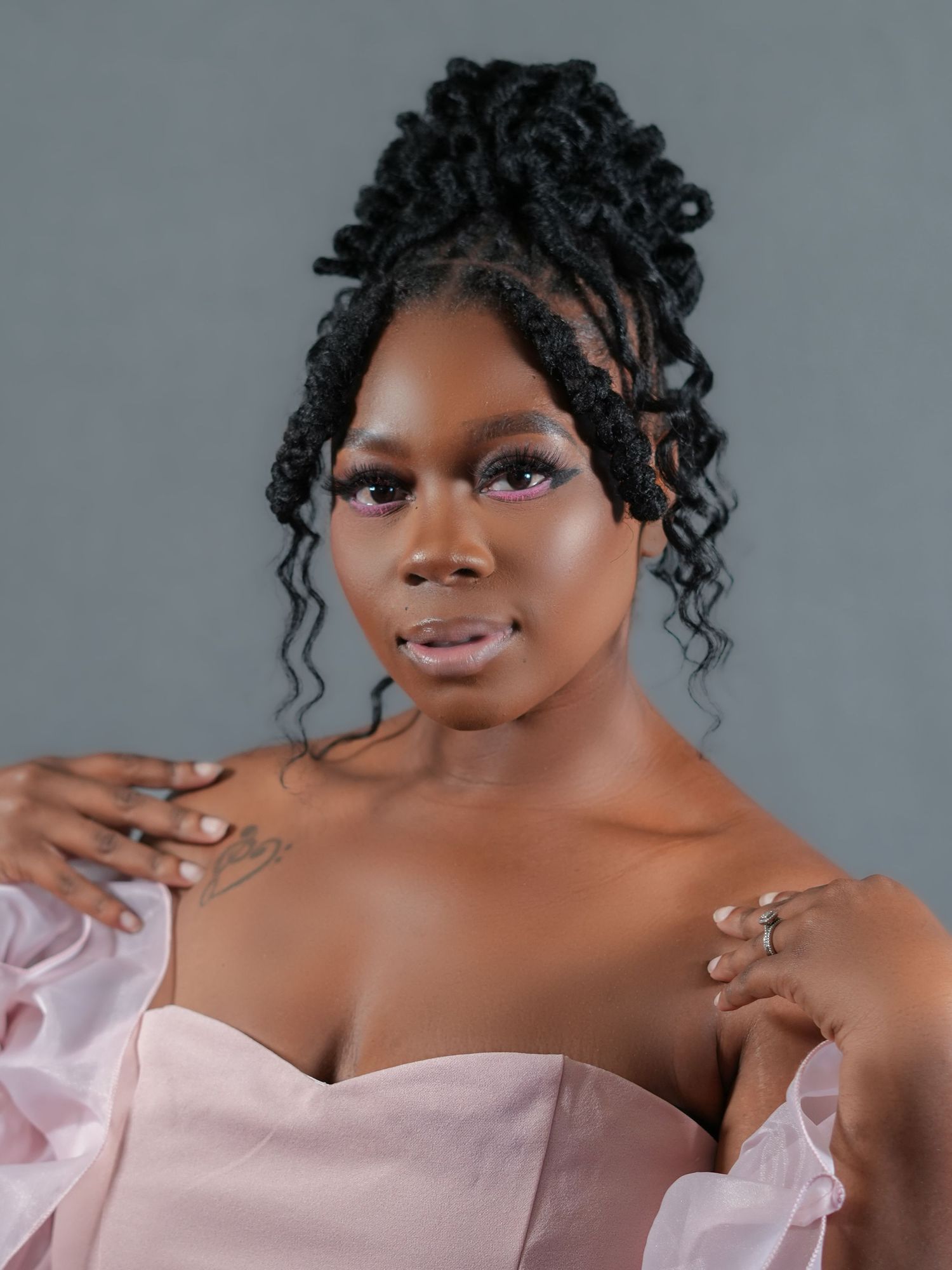 Portrait of woman in pink off-shoulder dress with elegant updo hairstyle.