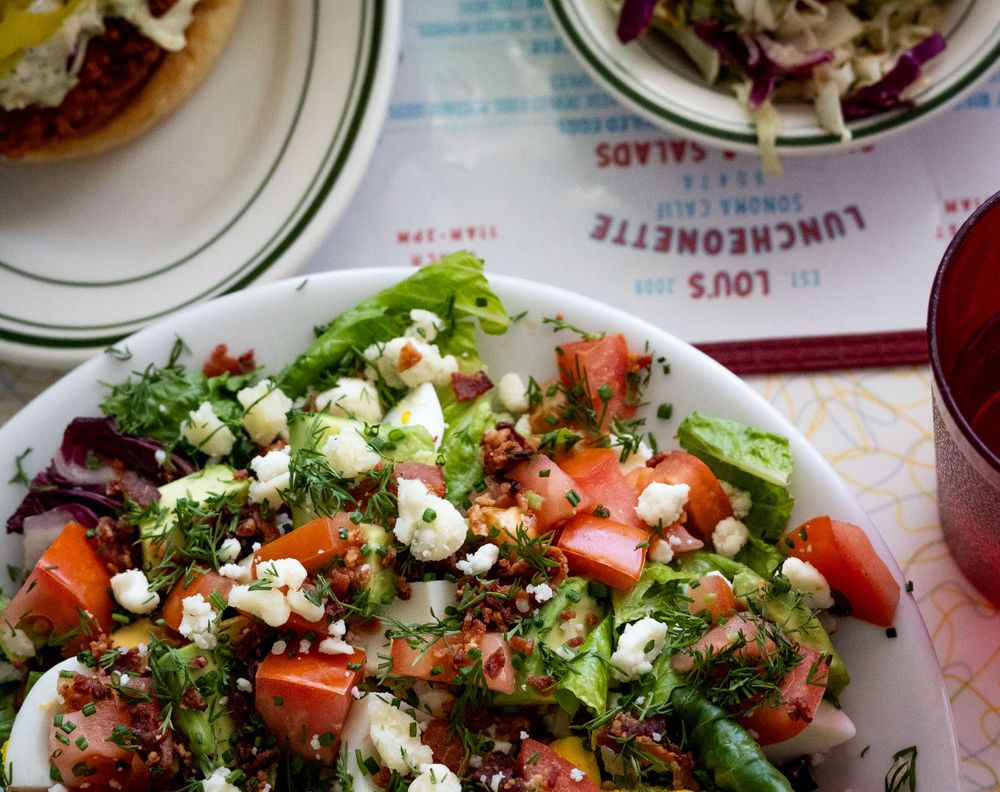 Fresh Greek salad with feta cheese, tomatoes and olives on a white plate.