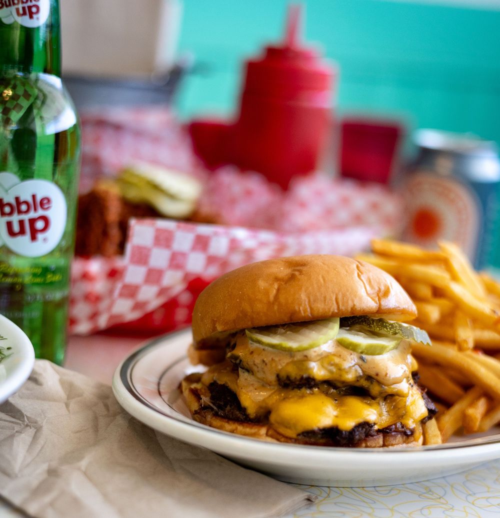 Classic cheeseburger with melted cheese and pickles served with french fries and a Bubble Up soda.