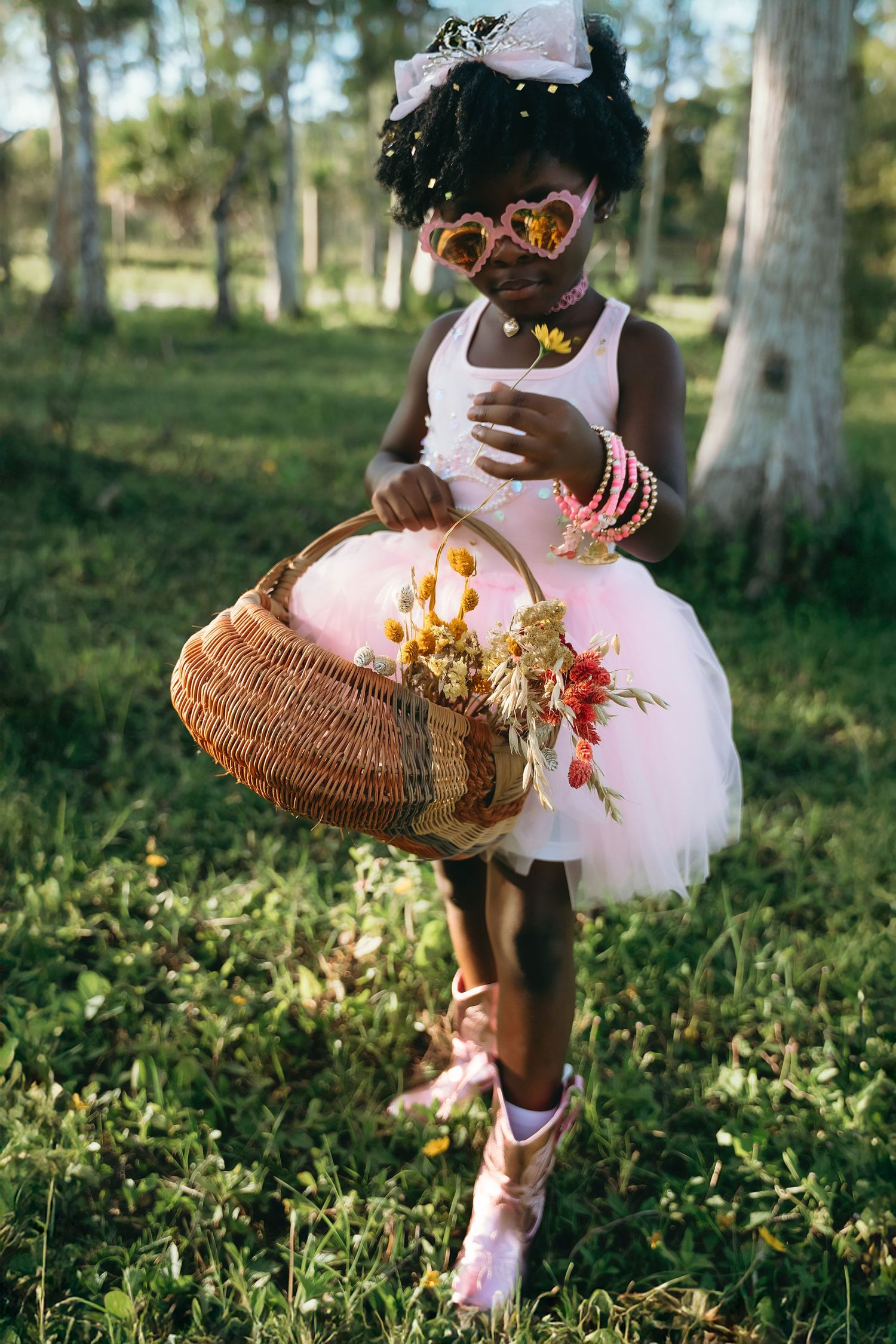 Figure in a pink tutu dress forages in the woods with a woven basket, capturing a whimsical autumn scene.