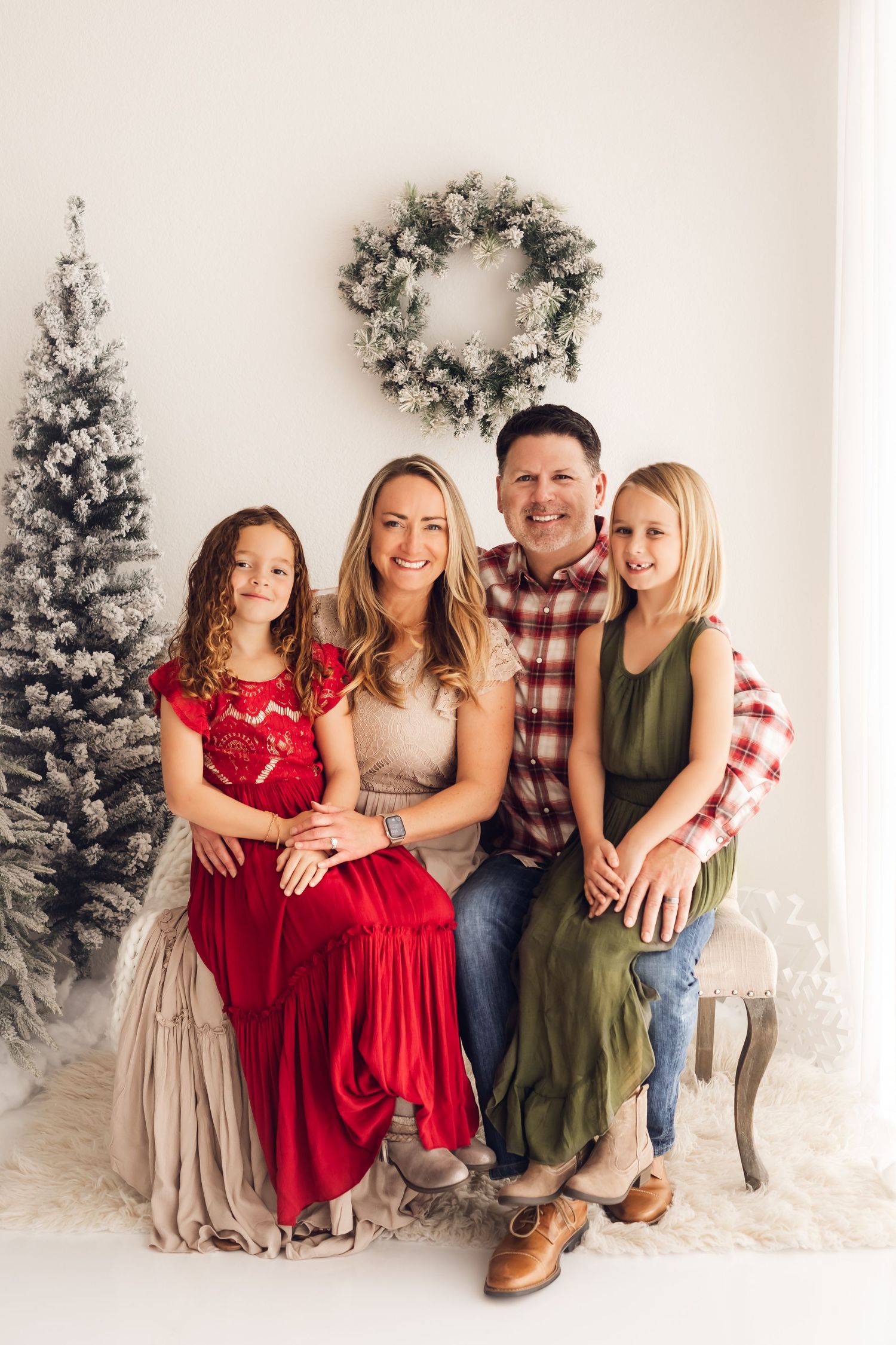 Family of four dressed in Christmas attire for their studio themed Christmas mini session portrait.