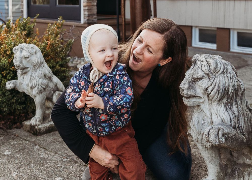 A joyful outdoor moment captured between two people next to decorative stone lion statues.