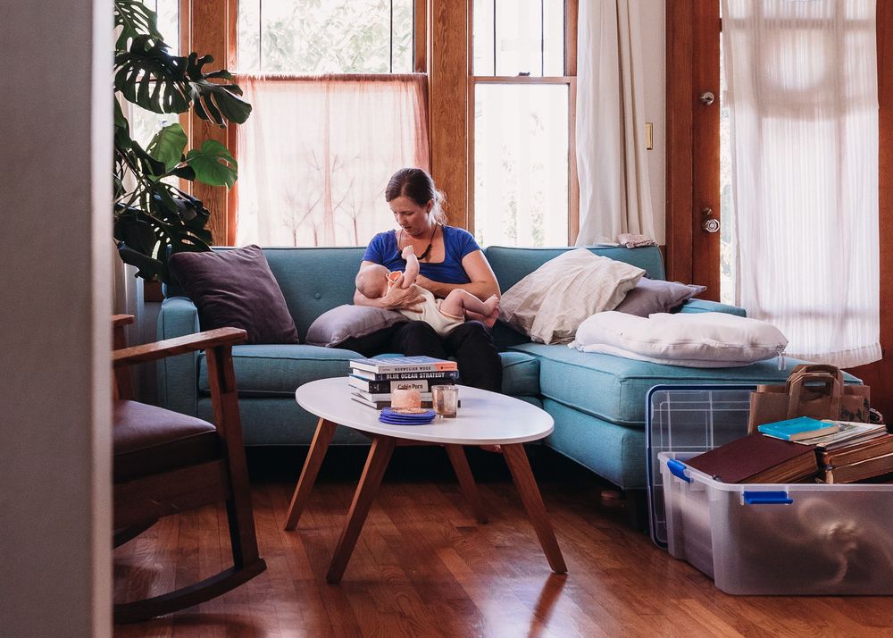 A cozy sunlit living room with a blue sectional sofa and round coffee table on hardwood floors.