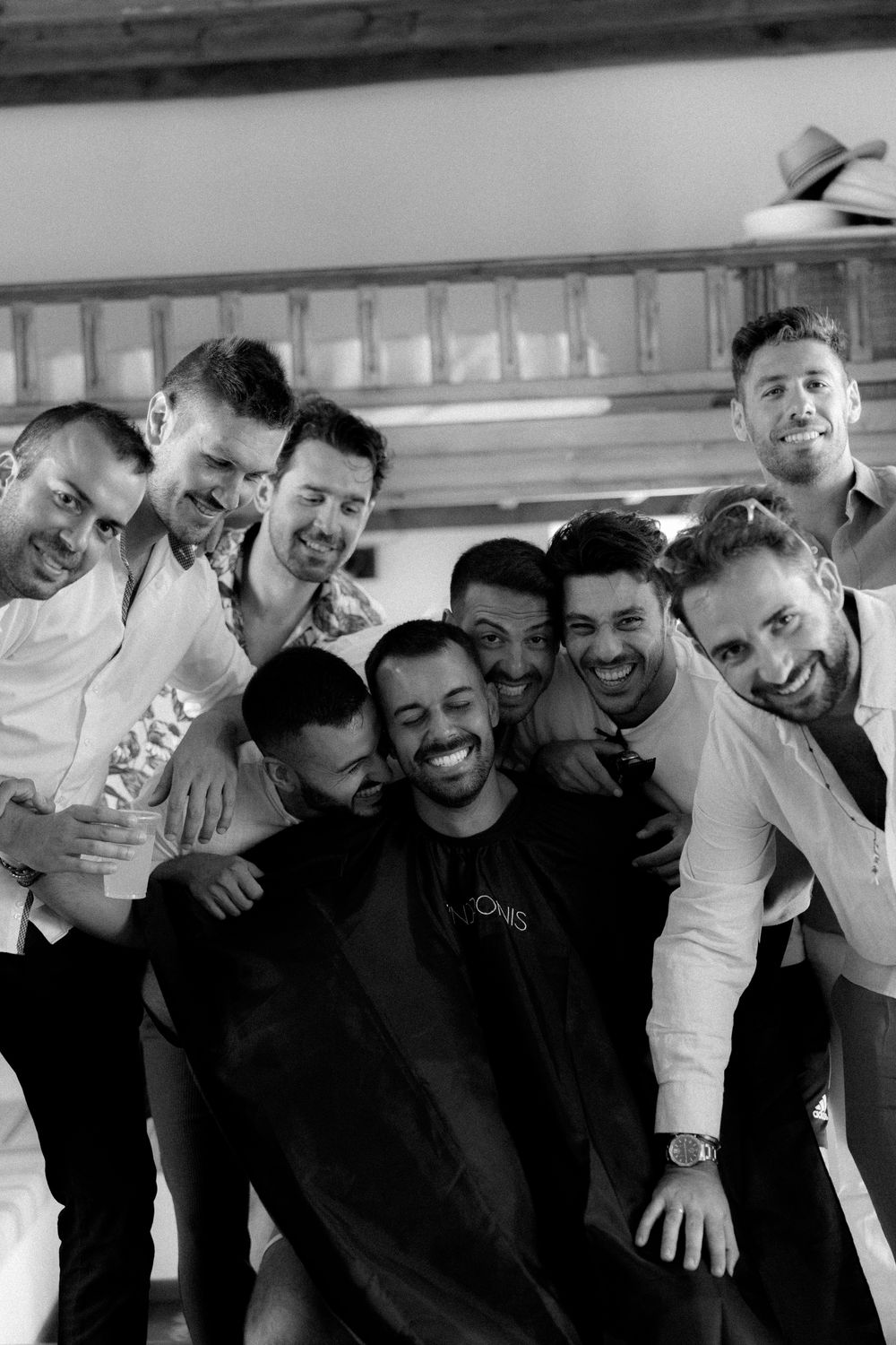 Group photo of wedding party members in white shirts sharing a candid moment. Astypalaia wedding photographer Greece