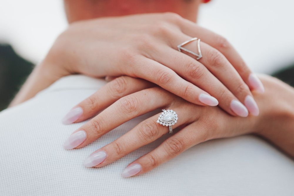 Close up of hands wearing elegant engagement ring and geometric band with perfectly manicured nails.
Engagement shoot ideas