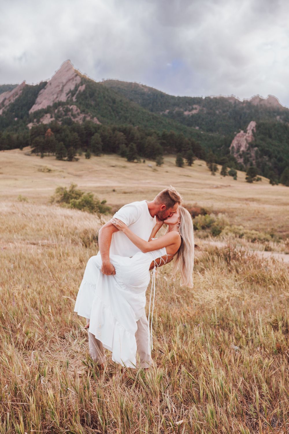 A romantic scene with dancing in a white dress against golden-lit mountainous terrain with jagged peaks in the background.