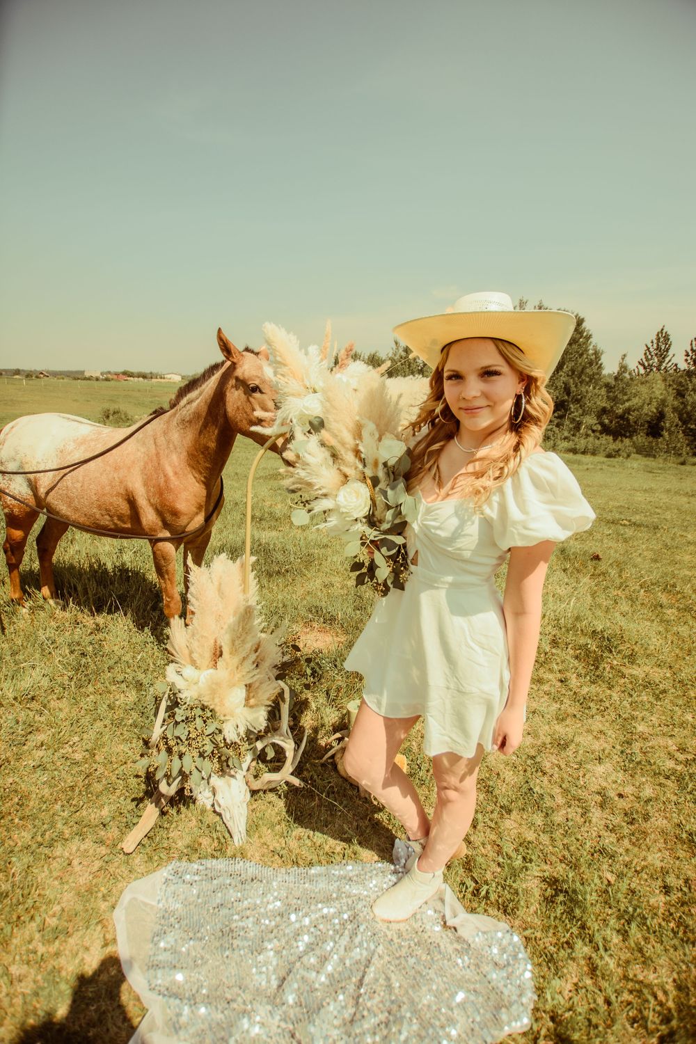 A rustic outdoor scene with a horse and floral arch decorations in a sunlit meadow on a warm summer day.
