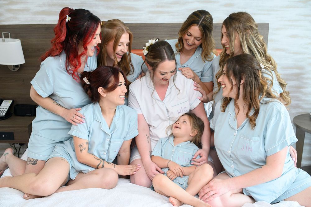A group in matching light blue sleepwear sits together on a bed, sharing laughter and smiles.