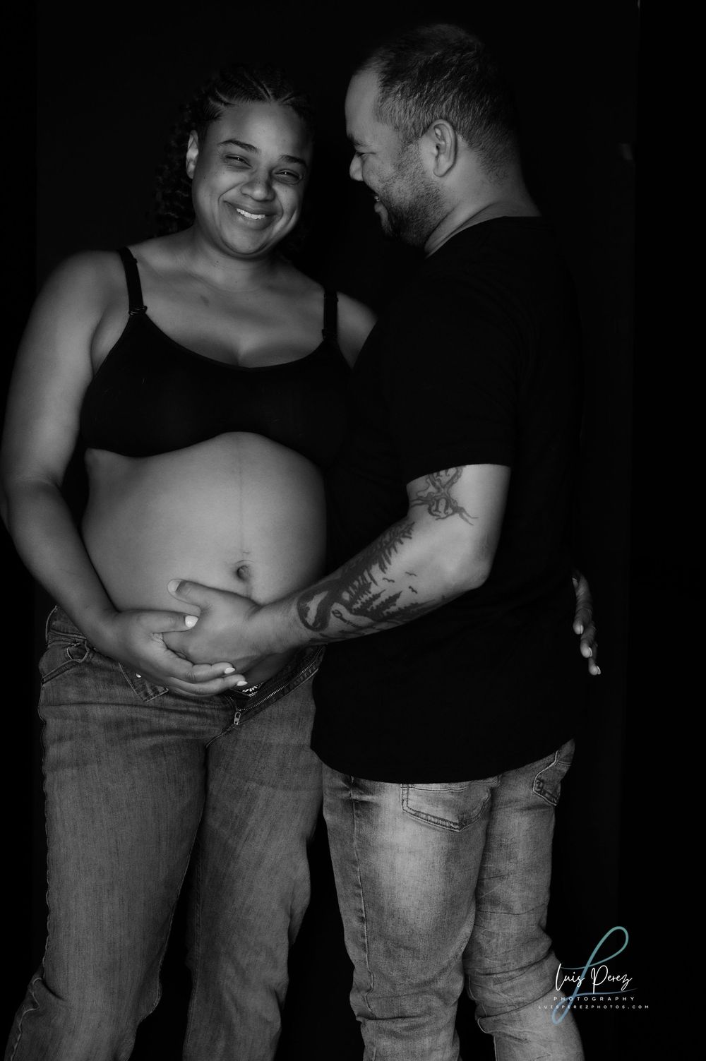 A black and white maternity photo showing an expectant couple sharing a tender moment together.