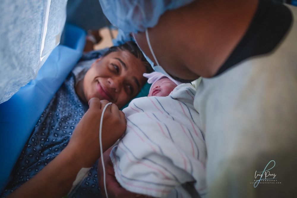 A tender moment captured in a hospital room as a parent meets their newborn baby for the first time.