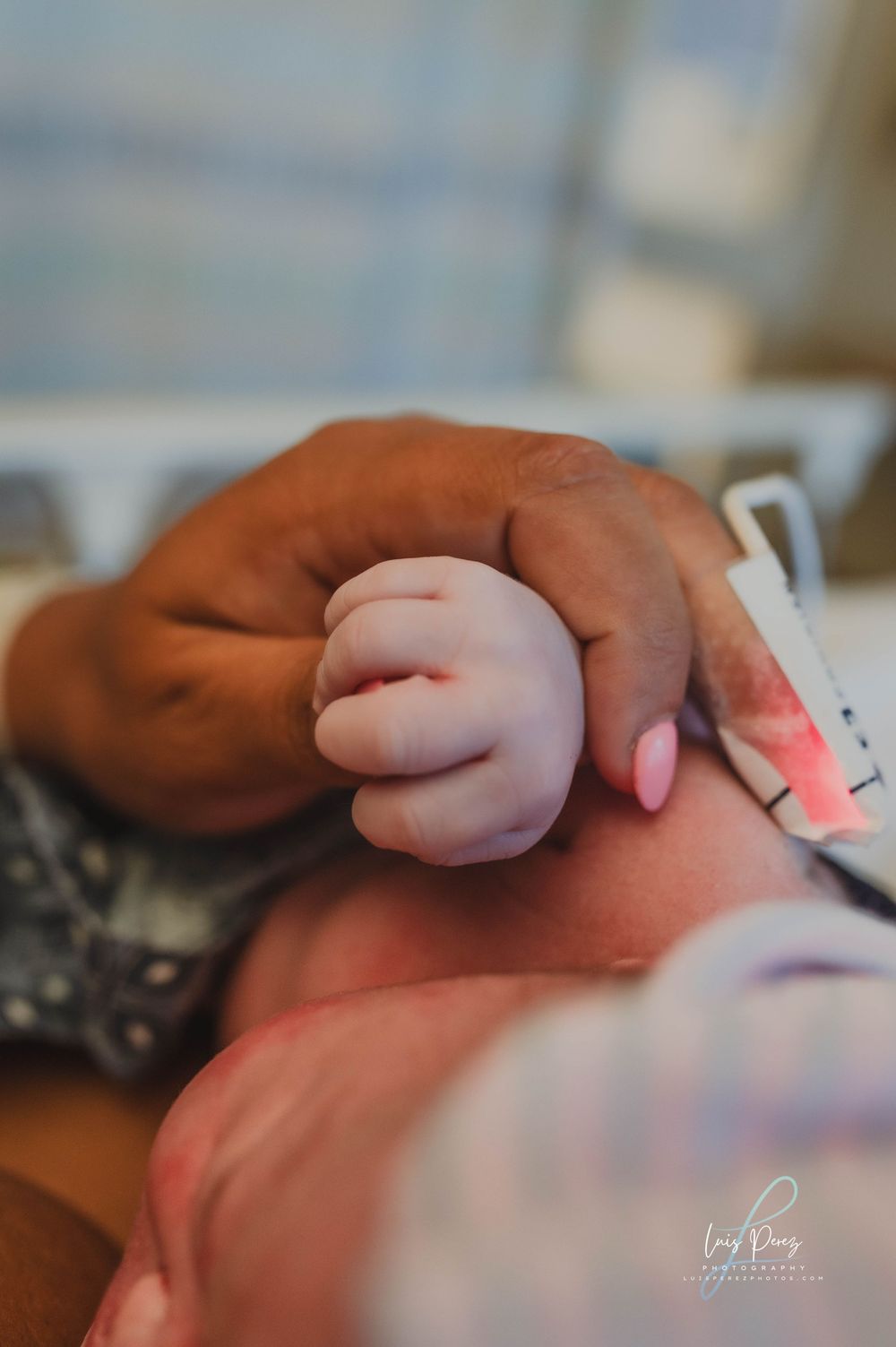 Close-up shot of a tiny baby hand grasping an adult's finger in tender moment.