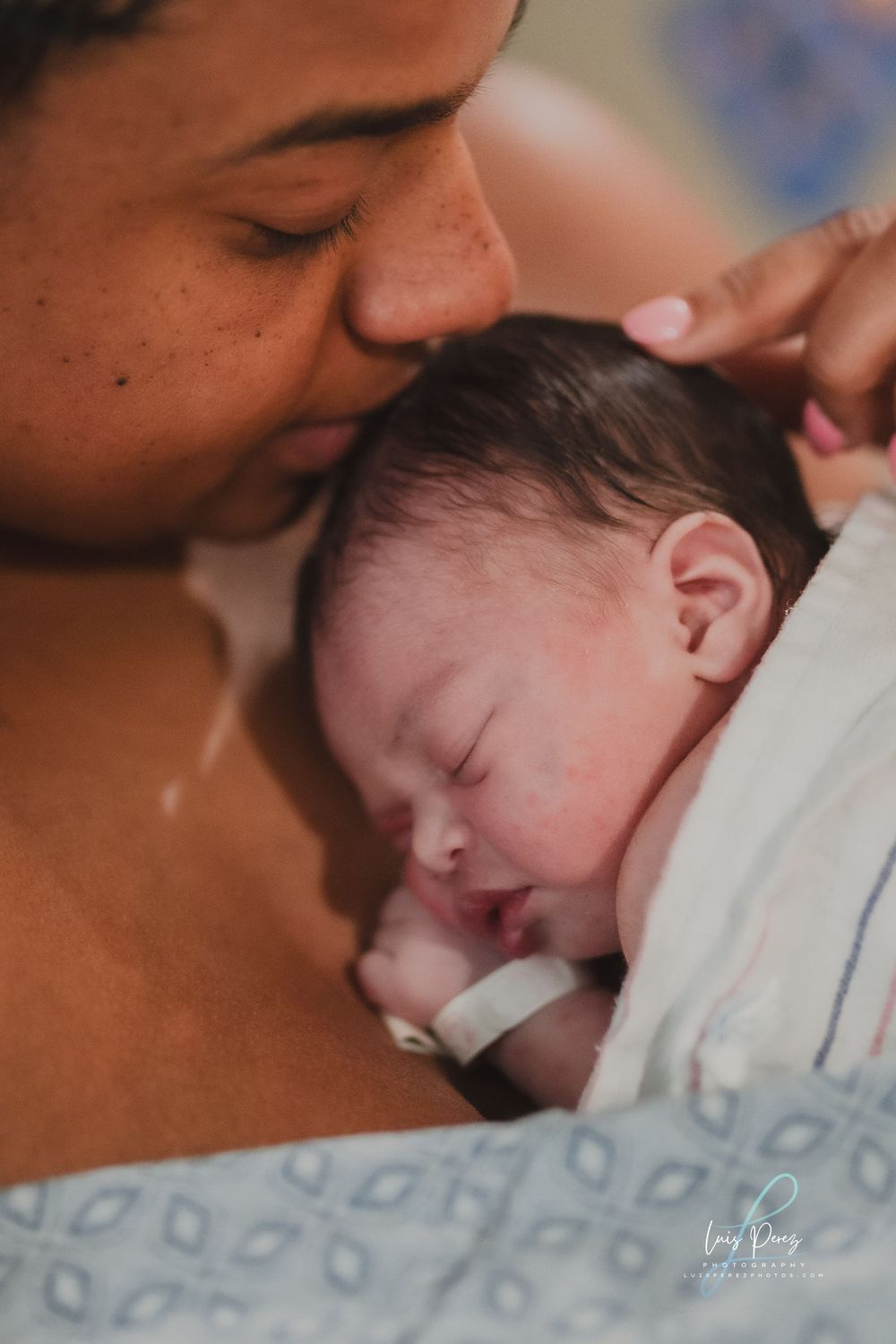 Tender newborn photo session showing parent and baby in soft black and white tones with gentle lighting.