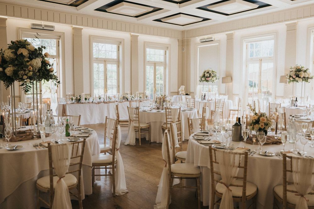 Elegant white wedding reception venue with crystal chandeliers and round tables set for a formal celebration.